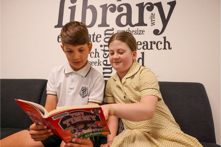 2 students reading together in the library.