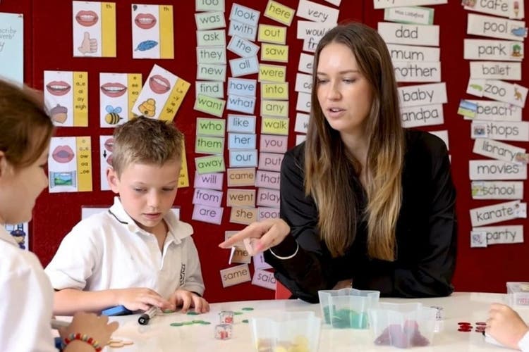 A teacher working closely with 2 students.