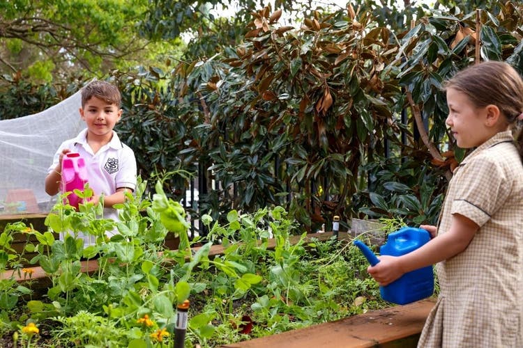 2 young students watering the garden.