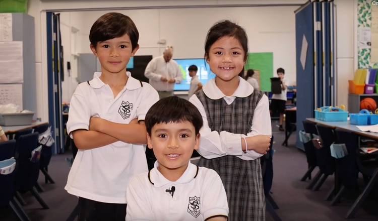 2 boys and 1 girl from year 3 with strong folded arms, standing in the classroom.
